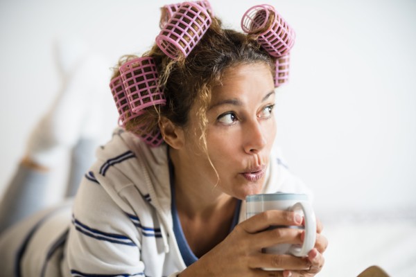Woman with hair curlers holding mug