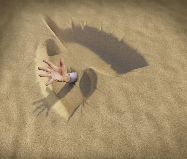 Hand reaching from lungs shaped sand