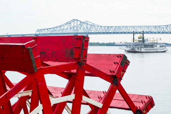 Mill wheel with Crescent City Connection bridge in distance in New Orleans, USA