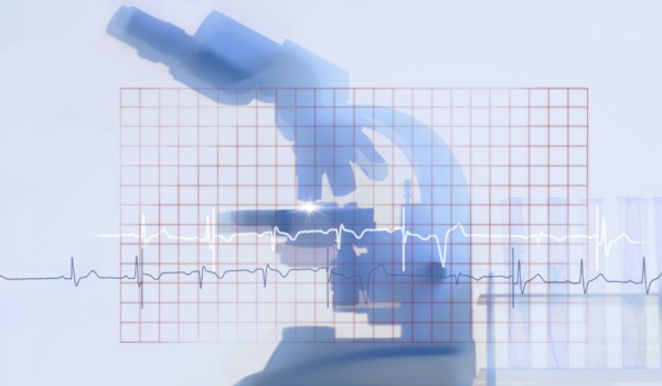 Silhouette of microscope behind electrocardiogram