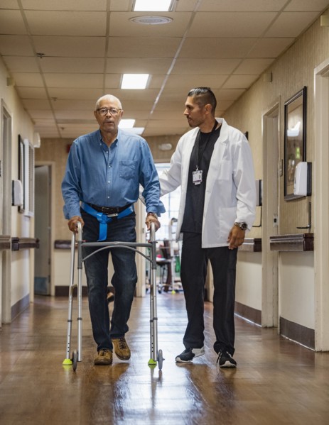 Doctor helping senior man use walking frame
