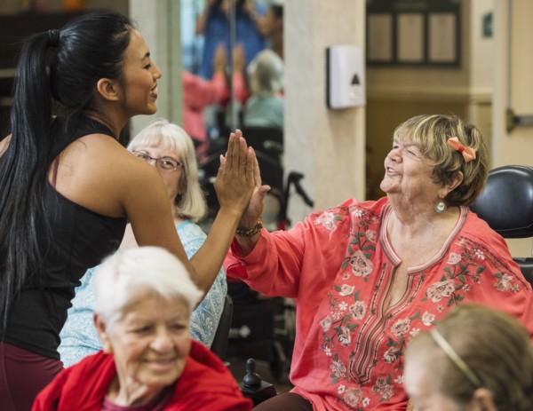 Smiling fitness instructor high-fiving smiling senior woman