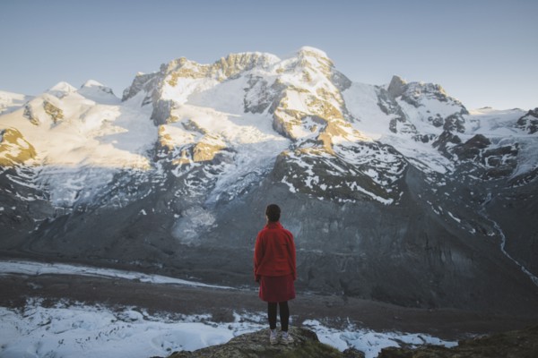 Woman standing on rock by Gorner Glacier in Valais, Switzerland