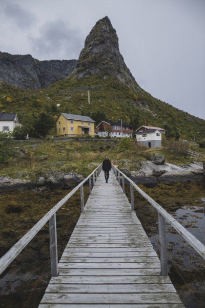 Man walking on bridge by cliff in Lofoten Islands, Norway