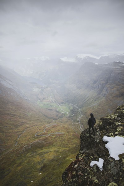 Man standing on Dalsnibba mountain overlooking valley in Geiranger, Norway