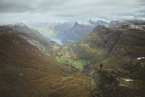 Man standing on Dalsnibba mountain overlooking valley in Geiranger, Norway