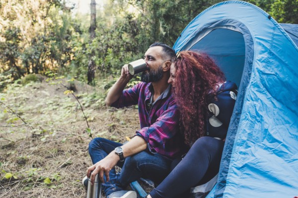 Smiling couple drinking by tent