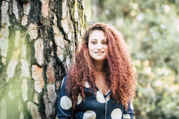 Smiling brown haired woman by tree