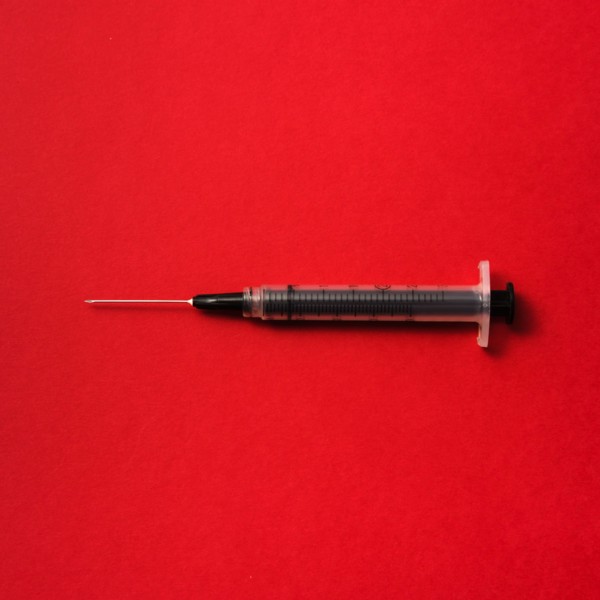 Syringe on red background