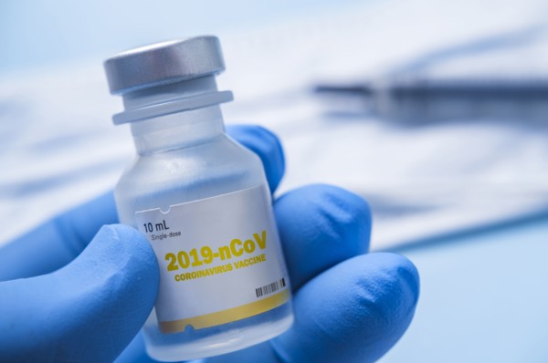 Close-up of gloved hand holding vial of Coronavirus vaccine