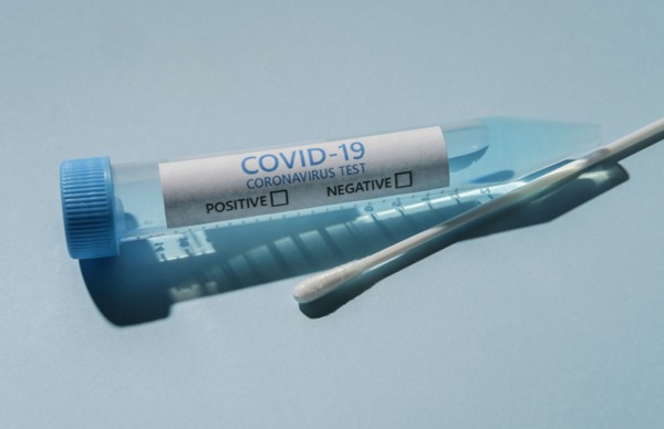 Covid-19 test vial and swab on blue background