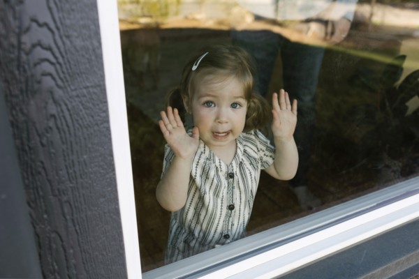 Girl (2-3) looking through window