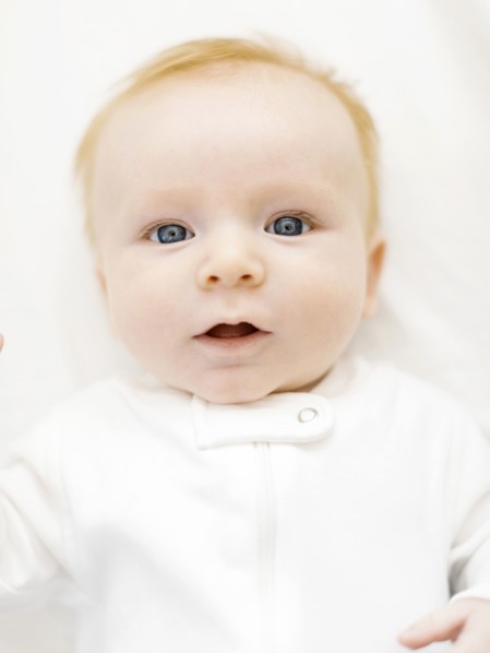 Portrait of baby boy (2-3 months) lying on bed