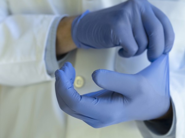 Close-up of doctor putting on blue latex gloves