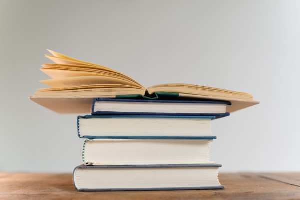Open book on top of stack of books on desk