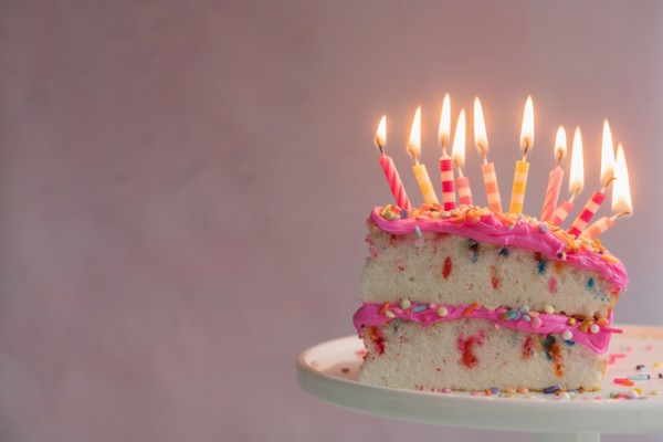 Slice of birthday cake with lit candles