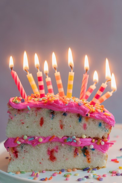Slice of birthday cake with lit candles