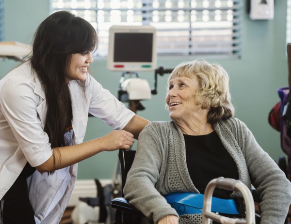 Nurse assisting senior woman in wheelchair in retirement home
