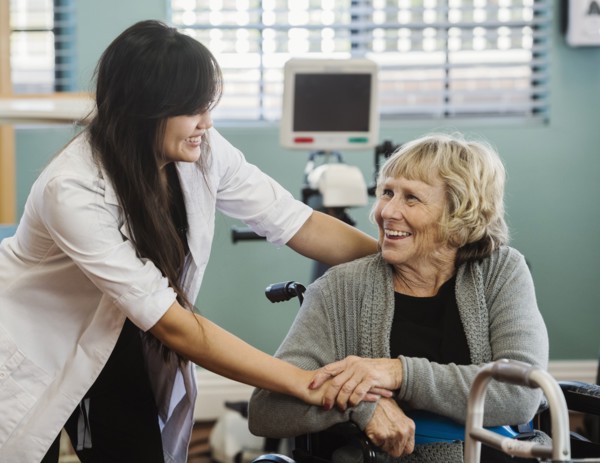 Nurse and senior woman holding hands in retirement home