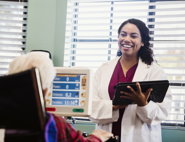 Doctor holding tablet and talking to senior man during exercising