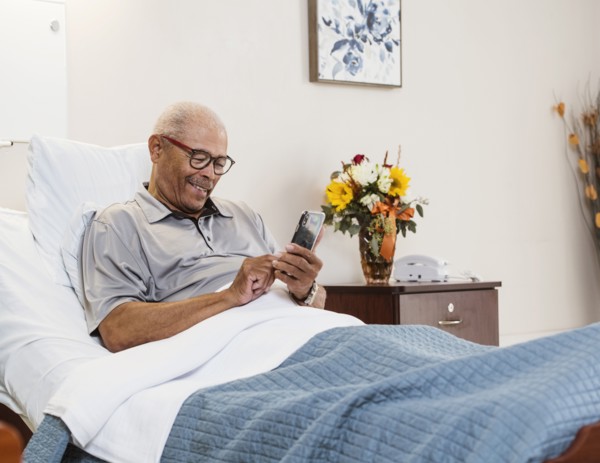 Senior man lying in bed and using smart phone