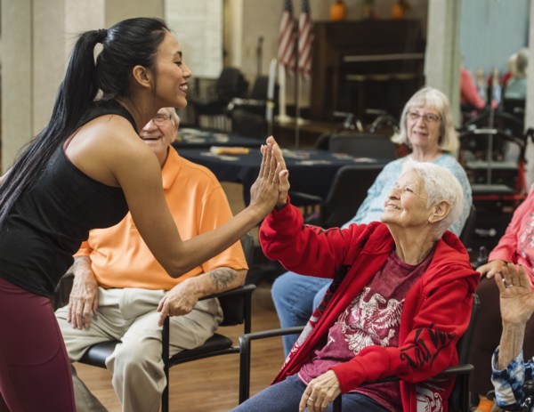 Senior woman high-fiving fitness instructor