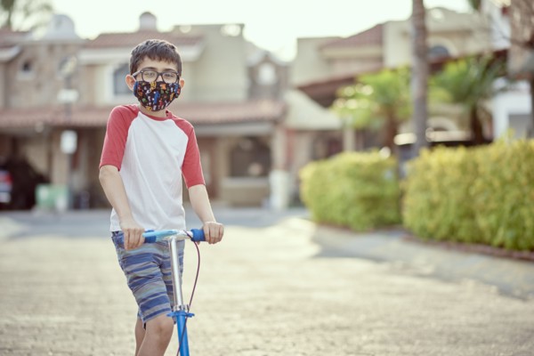 Mexico, Zapopan, Boy with face mask riding scooter