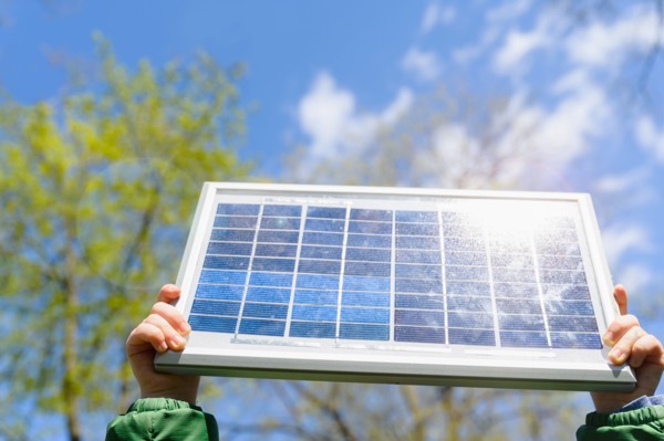 Close-up of boys (4-5) hands holding solar panel against sky