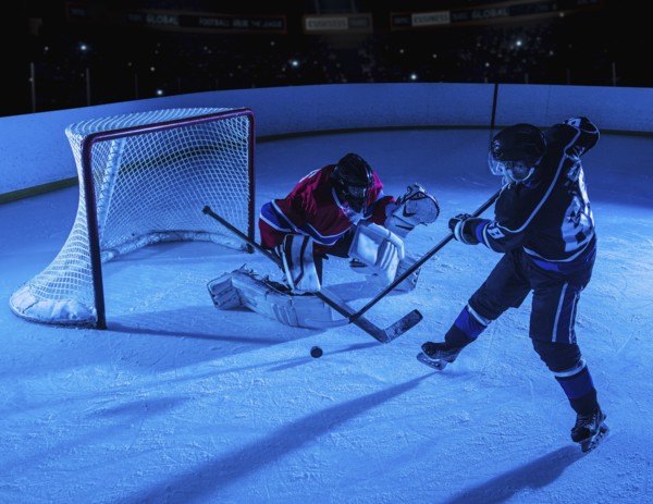 Hockey goalie defending net against forward