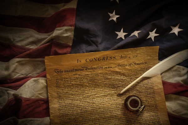 Declaration of independence, quill and ink lying on American flag,