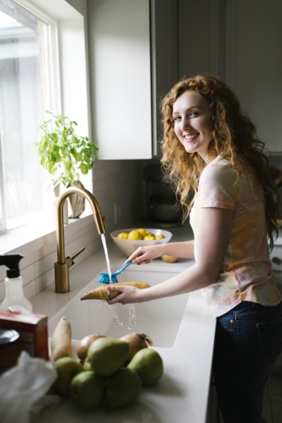 Woman washing sweet potato with brush