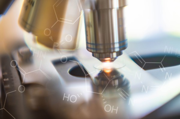 Close-up of laboratory microscope lens with chemical symbol