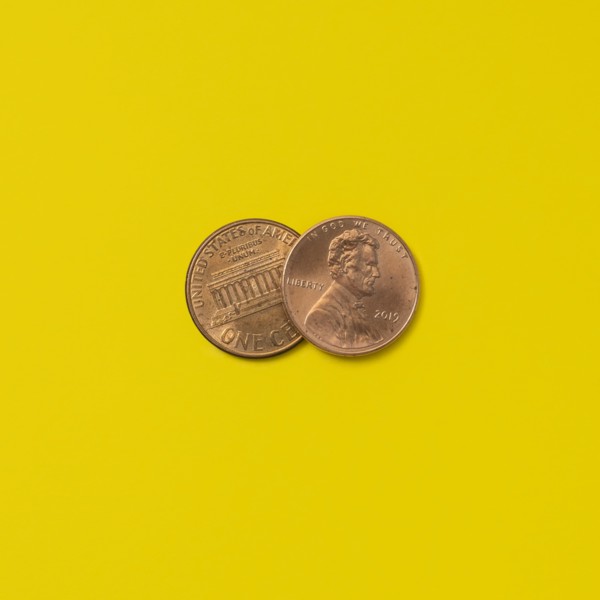 Front and back of two pennies on yellow background