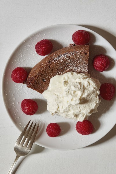 Chocolate cake with whipped cream and raspberries on plate