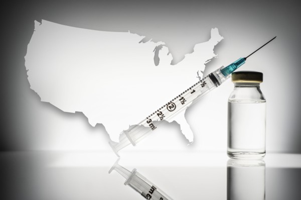 Studio shot of laboratory vial and syringe with USA shape in background