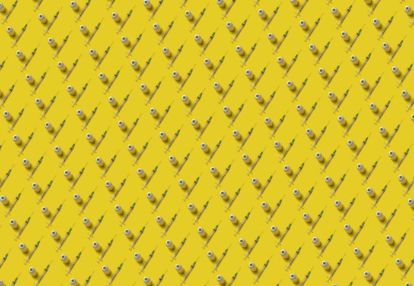Rows of laboratory vials and syringes on yellow background