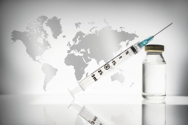 Studio shot of laboratory vial and syringe with world map in background