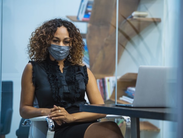 Portrait of businesswoman wearing face mask sitting at desk in office
