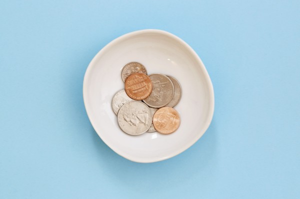 Coins in bowl on blue background
