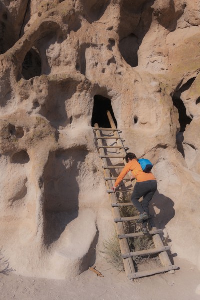 Woman climbing ladder to cliff dwellings in Bandelier National Monument