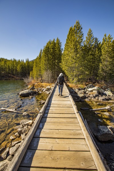 Senior woman walking on wooden path over Taggart Lake in Grand Teton National Park