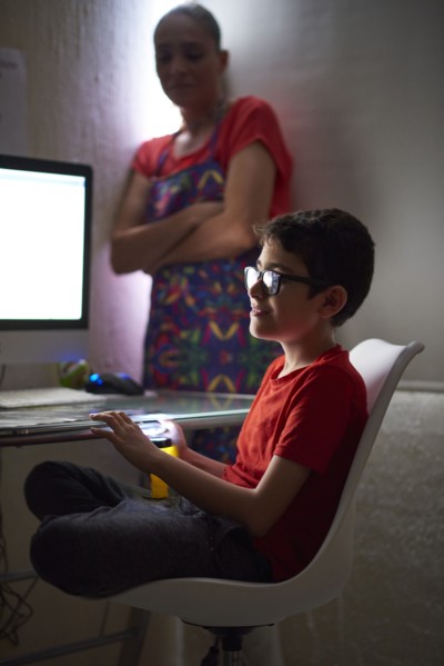 Mother watching son (8-9) during e-learning at home due to Covid-19 lockdown