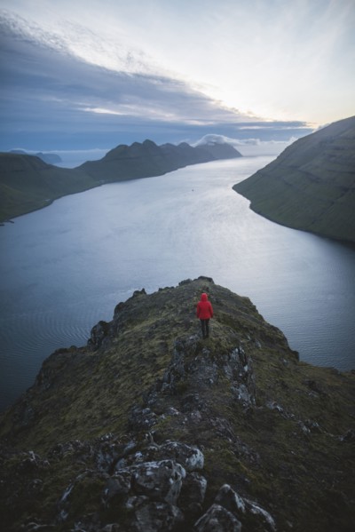 Woman standing on top of Klakkur mountain over sea and looking at view