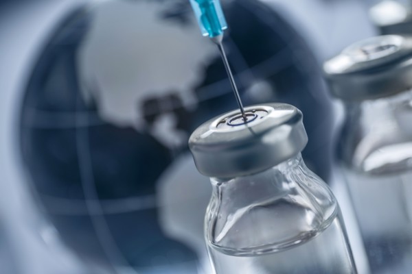 Vial of Covid-19 vaccine and syringe with globe in background