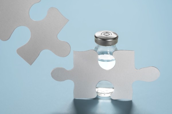 Vial of Covid-19 vaccine behind jigsaw puzzles