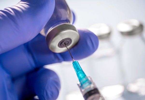 Close-up of gloved hand holding Covid-19 vaccine vial and syringe