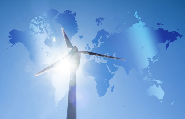 Wind turbine against blue sky and sun with world map in background