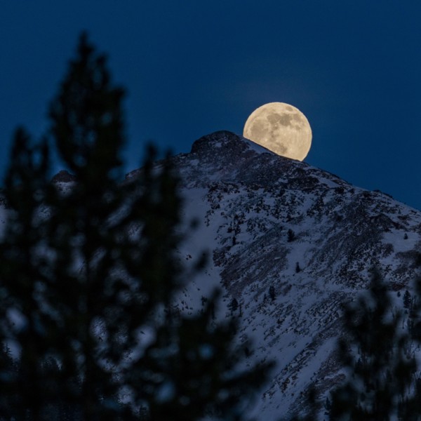 Full moon rising over Boulder Mountains in winter night