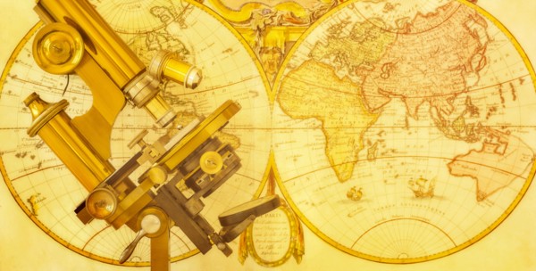 Old brass microscope against antique world map