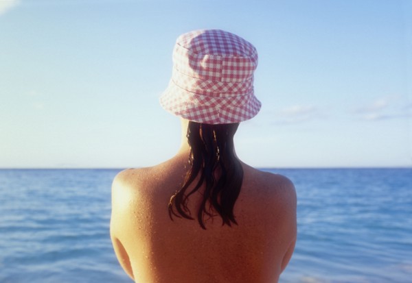 Rear view of woman in sunhat looking at sea